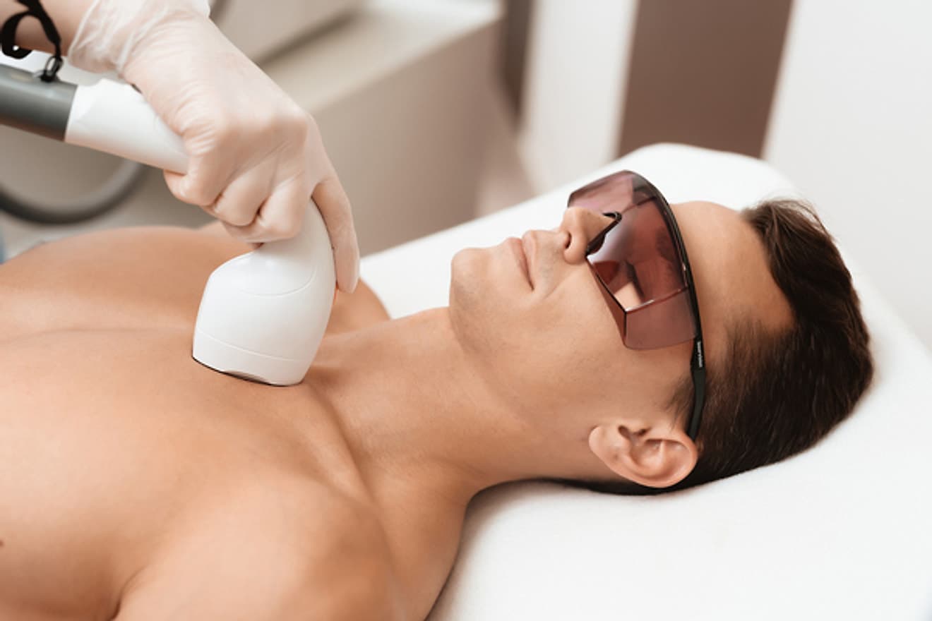 Koruyucu gözlük takan erkeğe göğüs bölgesinde lazer epilasyon uygulaması