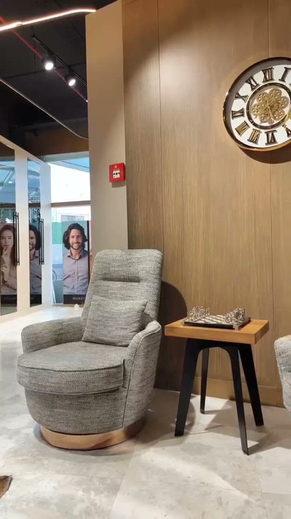 Salonun bekleme köşesi: berjer koltuk, satranç sehpası ve duvar saati
