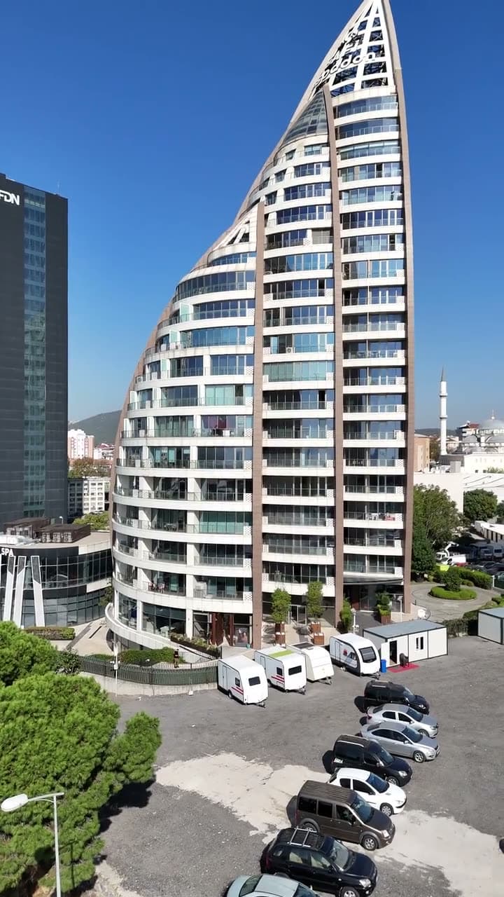 Havadan çekimde Safi Espadon Kule'nin yelken biçimli cephesi ve önündeki otopark